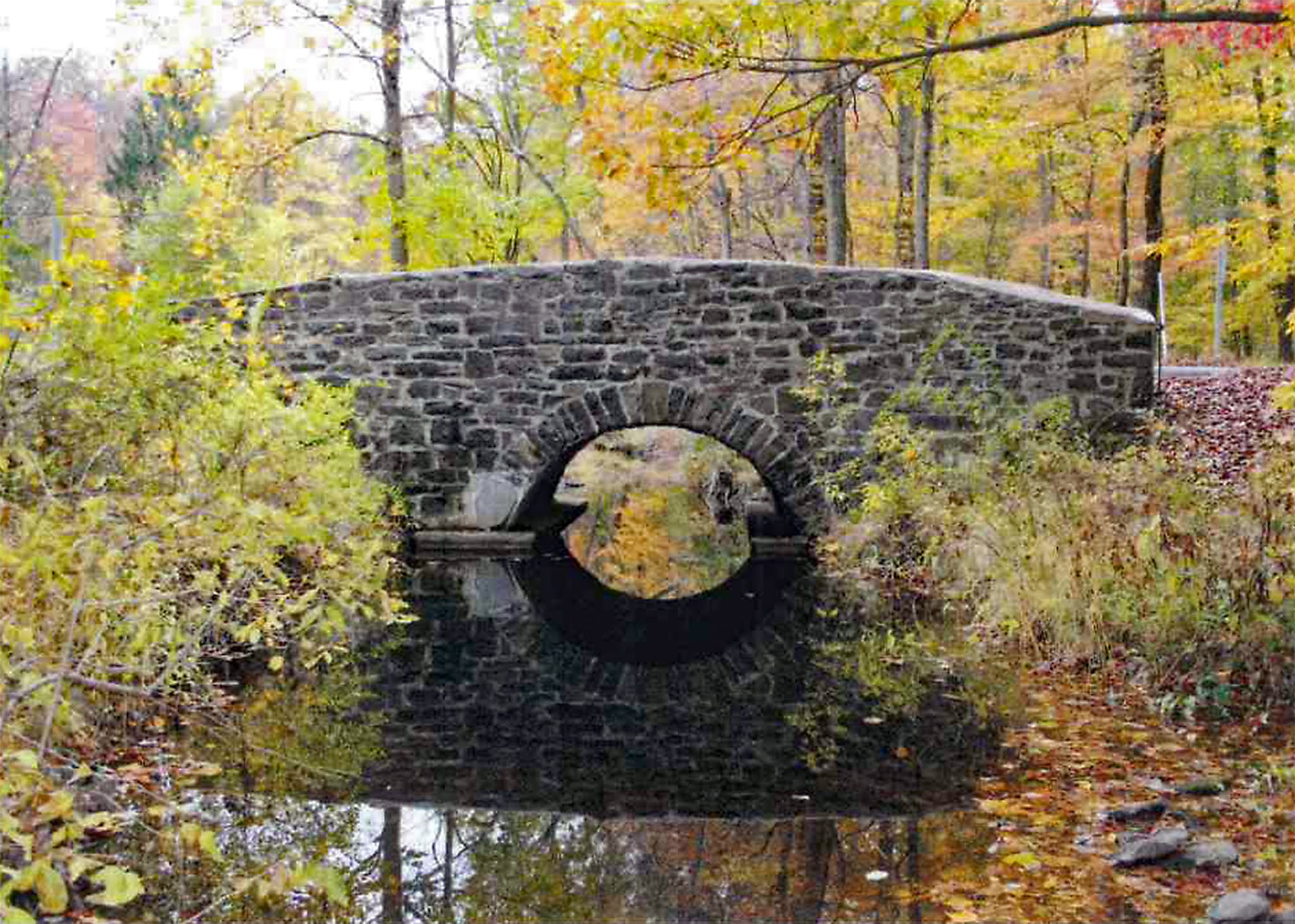 Historic stone arch bridge over Cattail Brook in autumn